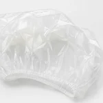 Close-up of clear PE disposable shower cap material and gathered elastic edge