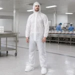Man in a white cleanroom suit with hood standing in a sterile manufacturing facility.